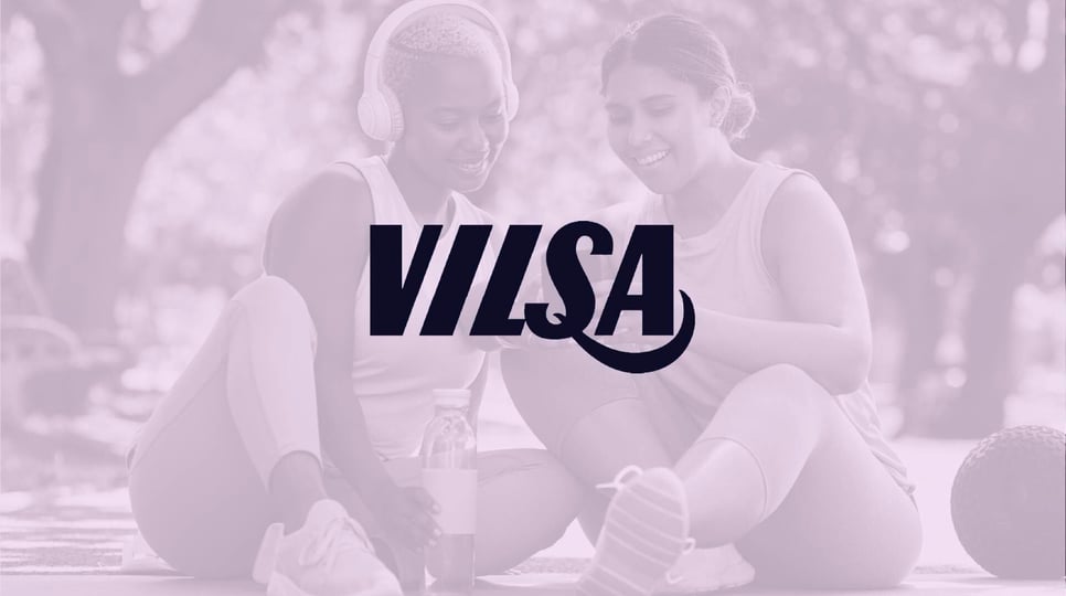 Two women in athletic wear sit outdoors, smiling and sharing a moment, overlaid with the "VILSA" logo in bold typography.