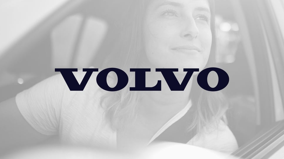 Woman smiling and looking out of the window of her Volvo SUV in black and white, with the Volvo logo in the center